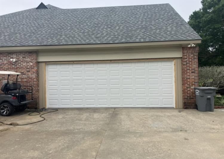 Newly installed white panel garage door on a brick home