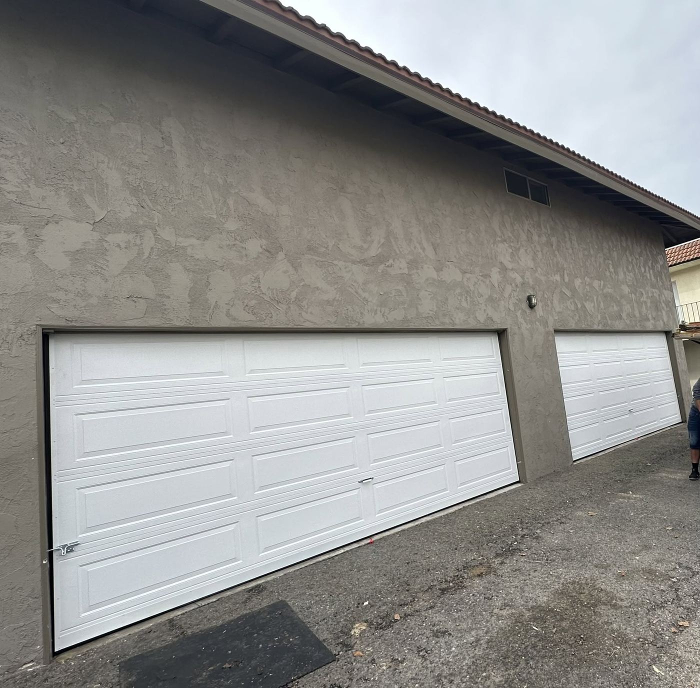 New white panel double garage doors installed on a stucco home
