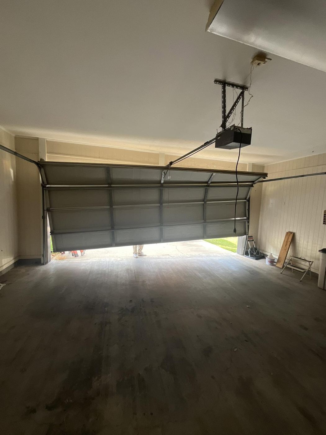 Interior view of a garage door and opener mid-service