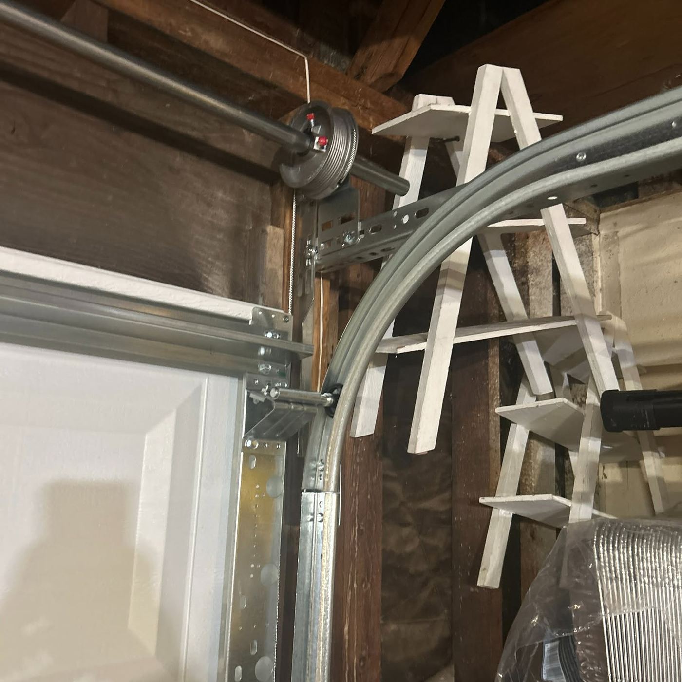 Garage door torsion spring and cable drum system mounted above the door